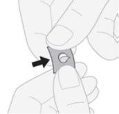 Ręka trzymająca szary plasterkowy lek z białym centralnym kręgiem i czarną strzałką wskazującą jego aplikację