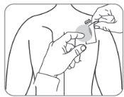 Hand applying a circular medicinal patch on the upper arm skin of a person