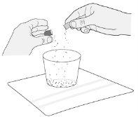 Hands opening a package over a glass with liquid and a white gauze on a flat surface
