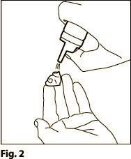 Mano che stringe un dispositivo per iniezione con ago esposto e goccia di liquido in punta
