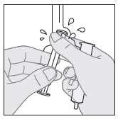 Mano che fissa un adattatore grigio su una siringa trasparente con gocce di liquido attorno