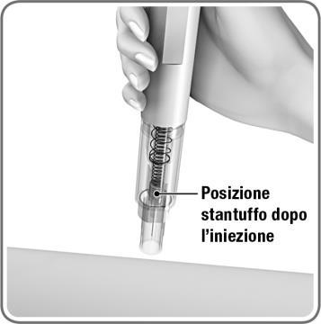 Siringa autoinsettante con meccanismo a molla visibile e ago trasparente, freccia indica posizione stantuffo post iniezione