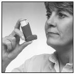 Donna che tiene un inalatore per asma nero e bianco con le dita della mano destra vicino alla bocca