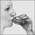 Paziente che utilizza un inalatore orale con bocchino posizionato tra le labbra e mani che lo sostengono