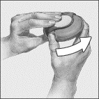 Mani che tengono un dispositivo medico rotondo e marrone con una freccia bianca che indica il movimento di rotazione