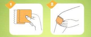 Mano che applica un cerotto adesivo sulla pelle con una garza centrale e due frecce numerate che indicano i passaggi 1 e 2