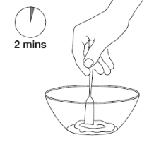 Mano che tiene una provetta immersa in un recipiente con liquido e un timer che indica 2 minuti