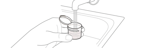 Mano che tiene un flacone di vetro aperto sotto il getto d