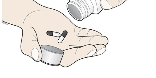 Mano che tiene due capsule farmaceutiche bianche e nere sopra un tappo metallico argentato