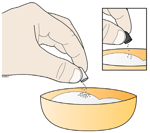 Mano che versa polvere da una bustina in una ciotola gialla contenente altri granuli simili