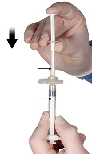 Mano con guanto che tiene una siringa preriempita trasparente con liquido ambrato e stantuffo bianco freccia nera indica la preparazione
