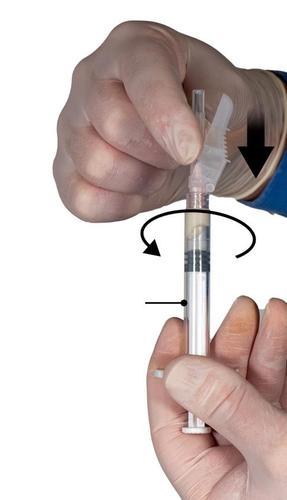 Mano guantata che ruota una siringa preriempita con ago trasparente e indicazioni frecciate per la corretta somministrazione