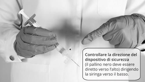 Mano con guanto che tiene una siringa pronta per l