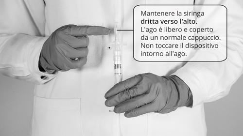 Mani con guanti che tengono una siringa, l