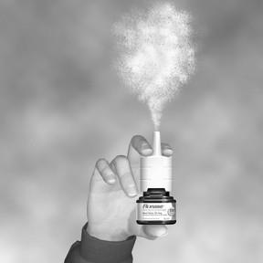 Mano che tiene un inalatore nasale bianco con erogazione di spray nebulizzato verso l