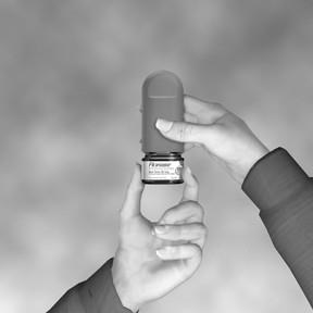 Mano che tiene un inalatore dosato di colore grigio e nero con etichetta bianca e scritta nera