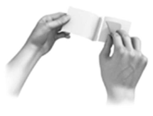 Mani che aprono un foglietto illustrativo piegato, mostrando il contenuto interno bianco su sfondo bianco