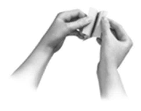 Due mani che aprono una bustina bianca e rettangolare, probabilmente contenente un farmaco o una dose singola