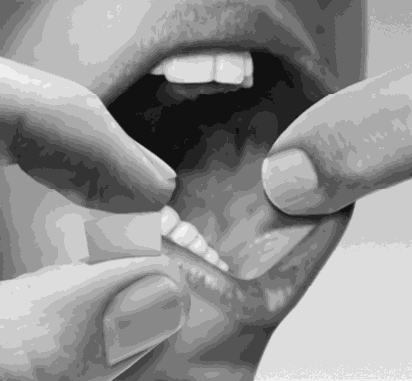 Mani che stringono una compressa bianca ovale tra pollice e indice preparandola per l