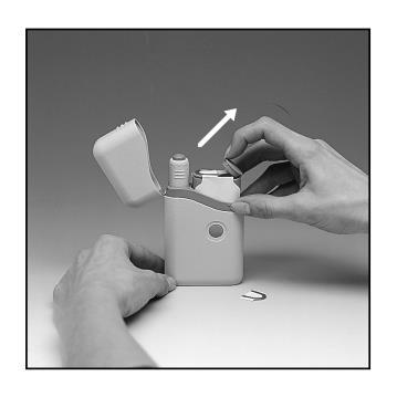 Dispositivo autoiniettante aperto con una mano che rimuove il cappuccio protettivo e ago di ricambio vicino