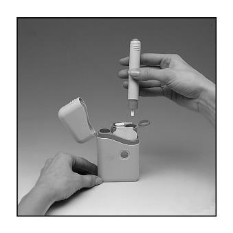 Mano che tiene un dispositivo autoiniettante con ago visibile sopra un contenitore aperto e bianco