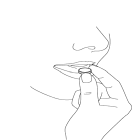 Mano che tiene una compressa rotonda tra pollice e indice sopra una superficie piana inclinata