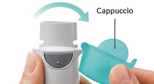 Inalatore con cappuccio protettivo azzurro parzialmente rimosso da una mano, freccia curva indica la direzione di apertura