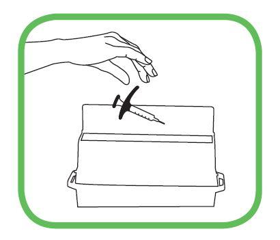 Siringa con ago rivolto verso il basso sopra un contenitore bianco rettangolare con coperchio verde