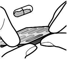 Mani che estraggono una compressa da un blister di alluminio contenente diverse compresse rettangolari