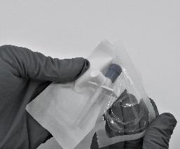 Mano con guanto che tiene una fiala di vetro trasparente sigillata in una busta di plastica protettiva