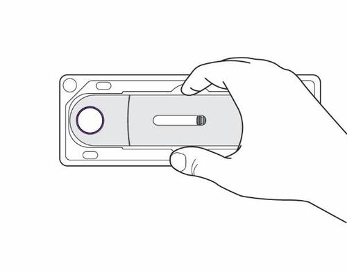 Mano che tiene un dispositivo rettangolare grigio con una finestra di visualizzazione viola e un pulsante circolare