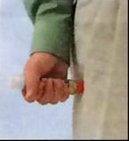 Mano che impugna una siringa preriempita con ago arancione collegato e protetto da cappuccio trasparente