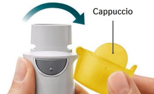 Inalatore bianco tenuto da una mano con cappuccio protettivo giallo parzialmente rimosso e freccia blu che indica la direzione