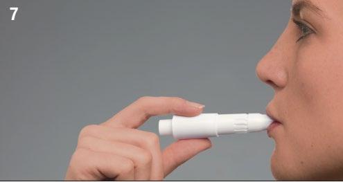 Persona che tiene un inalatore bianco alla bocca per l