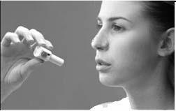 Donna che inala un farmaco da un inalatore spray bianco tenuto in mano vicino alla bocca aperta