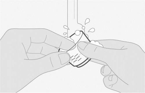 Mani che puliscono un dispositivo medico cilindrico con una soluzione schiumosa e gocce d