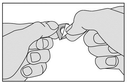 Mani che aprono un involucro metallico triangolare contenente il farmaco, preparazione all