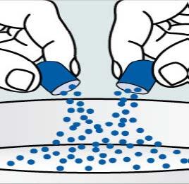 Due mani che aprono due capsule blu riversando granuli sferici blu su una superficie bianca sottostante