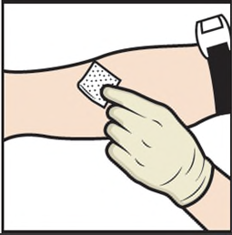 Mano con guanto che applica un cerotto adesivo bianco sulla pelle del braccio con movimenti delicati