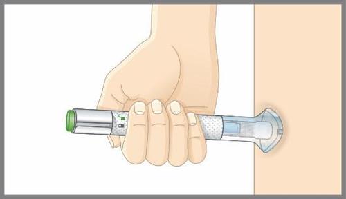 Mano che tiene un dispositivo per iniezione con ago trasparente premuto sulla coscia umana illustrata in tonalit&agrave; beige