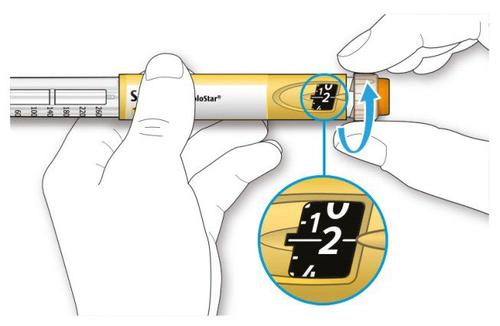 Mano che ruota il selettore di dosaggio su una penna per insulina NovoStar con indicazione della dose 1/2 unit&agrave; e freccia blu