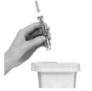 Mano che tiene una fiala di vetro trasparente sopra un contenitore bianco aperto per lo smaltimento