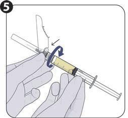 Mano con guanto che ruota il cilindro di una siringa per misurare il liquido giallo all