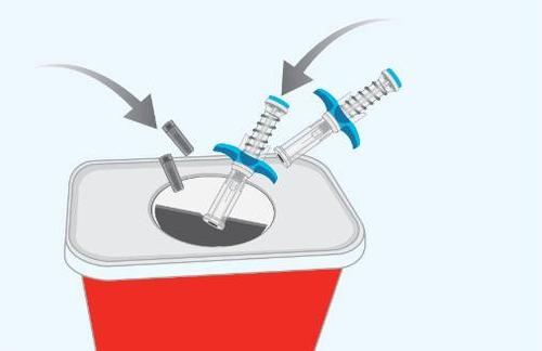 Siringhe usa e getta con aghi protetti inseriti in un contenitore rosso per rifiuti speciali frecce indicano la direzione