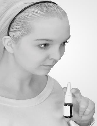 Donna che guarda verso il basso mentre tiene uno spray nasale in mano pronto all