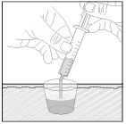 Mano che tiene una siringa sopra un bicchiere contenente liquido trasparente con un ago inserito nel contenuto