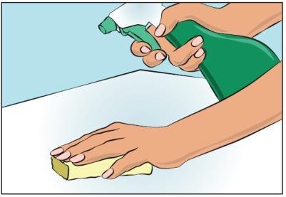 Mano che spruzza disinfettante verde su una superficie bianca e un