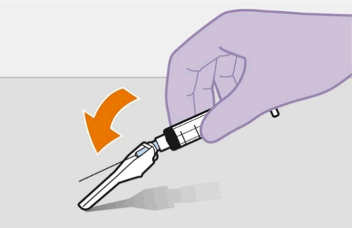 Mano con guanto viola che tiene una siringa con ago inserito ad angolo mostrando una freccia arancione che indica la direzione