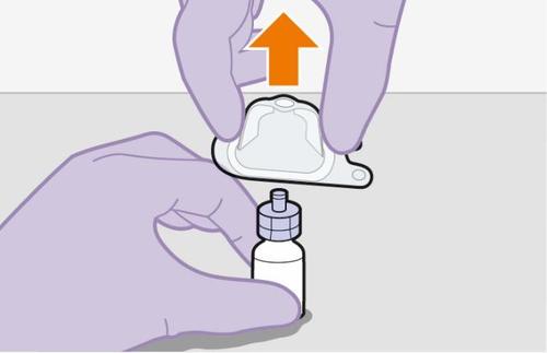 Mano con guanto viola che avvita un tappo su un flacone di medicinale con un dispositivo di trasferimento collegato