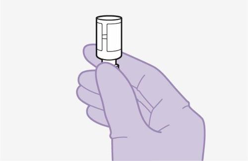 Mano con guanto viola che tiene un dispositivo medico cilindrico bianco con dettagli verticali grigiastri